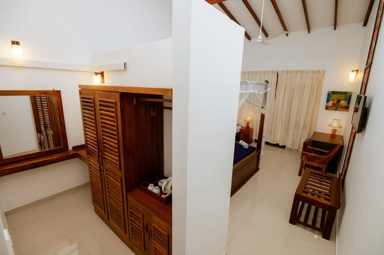 A wardrobe with a tea tray, wall mirror, and writing desk beside the bedroom