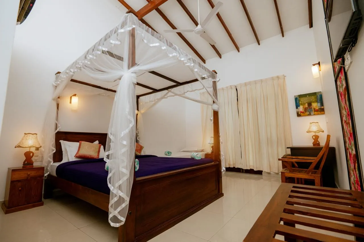 A canopy bed and writing desk beneath exposed ceiling beams