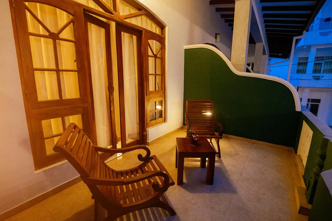 Two wooden chairs and a small table on a sheltered balcony at dusk