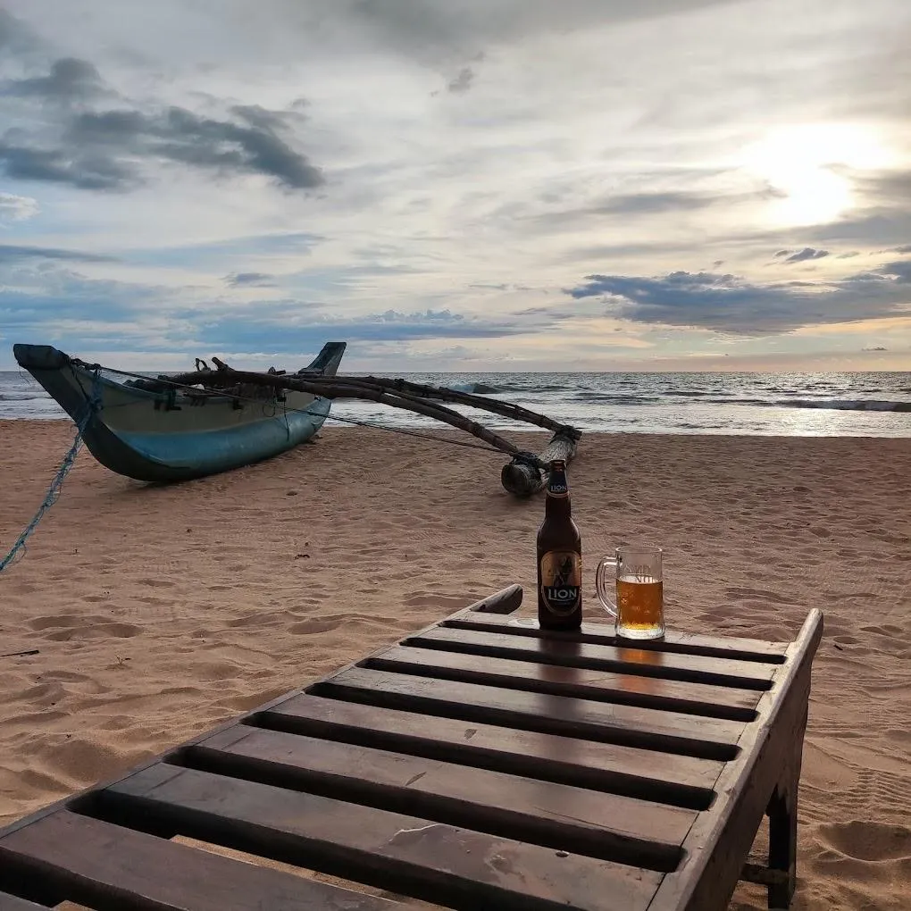 A fishing boat and a wooden lounger on the beach beneath an evening sky