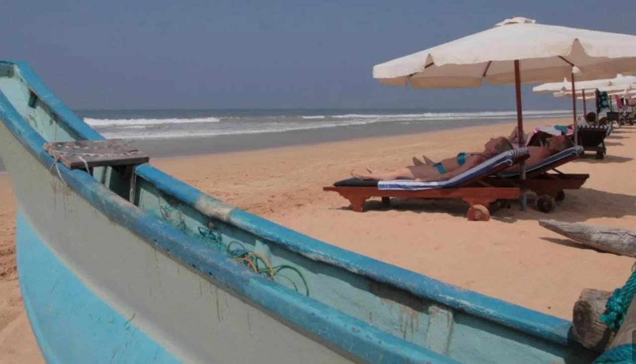 A fishing boat on the sand beside beach loungers and the sea